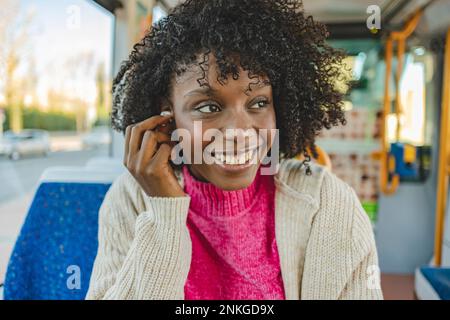 Bonne femme avec des écouteurs intra-auriculaires sans fil en tram Banque D'Images
