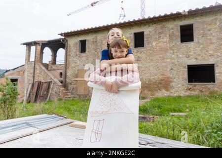 Des filles heureuses debout avec dessin devant la maison Banque D'Images