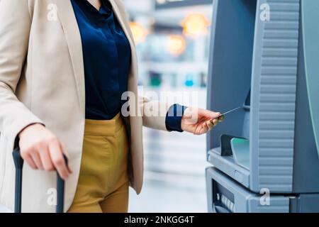 Main d'une femme d'affaires utilisant une carte de crédit au guichet automatique Banque D'Images