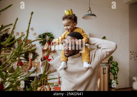 Joyeux homme avec sa fille touchant les décorations de Noël à la maison Banque D'Images