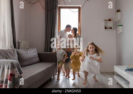 Les enfants qui coutent dans le salon, les parents frottant le nez en arrière-plan Banque D'Images