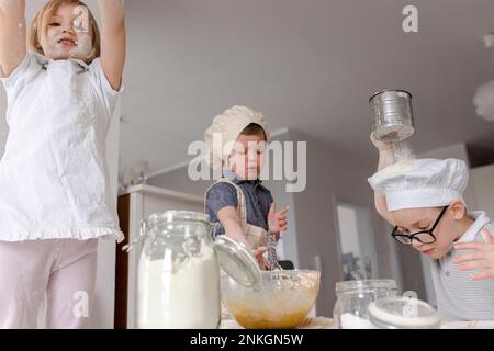 Fille avec frère préparant de la pâte dans la cuisine Banque D'Images