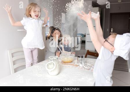 Enfants joueurs appréciant avec de la farine dans la cuisine Banque D'Images