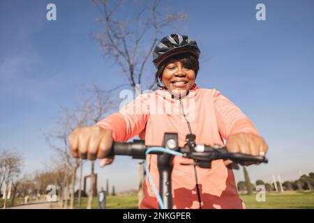 Femme senior tenant un guidon de scooter électrique Banque D'Images