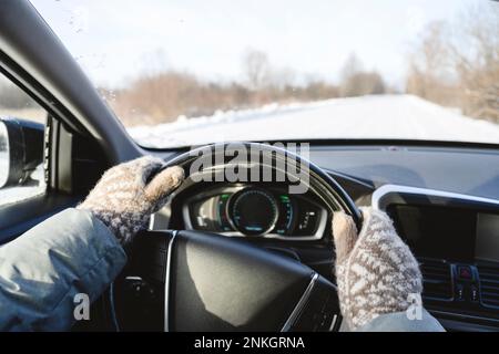 Homme portant des mitaines conduisant la voiture en hiver Banque D'Images
