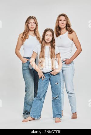 Mère et filles confiantes debout sur fond blanc Banque D'Images