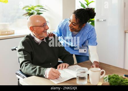 Un gardien heureux aidant l'homme senior à la maison Banque D'Images