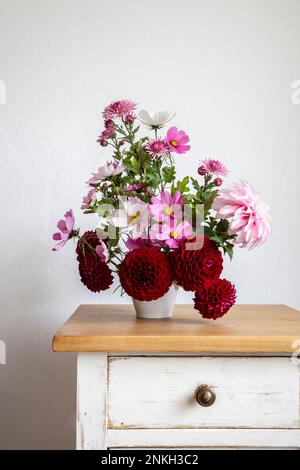 Bouquet de fleurs d'automne rouges et roses sur table de nuit Banque D'Images