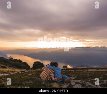 Couple d'âge mûr aimant assis sur la montagne sous le ciel Banque D'Images
