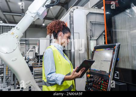 Jeune ingénieur exploitant des machines dans l'industrie Banque D'Images