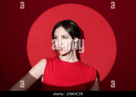 Femme souriante contemplative contre les projecteurs sur fond rouge Banque D'Images