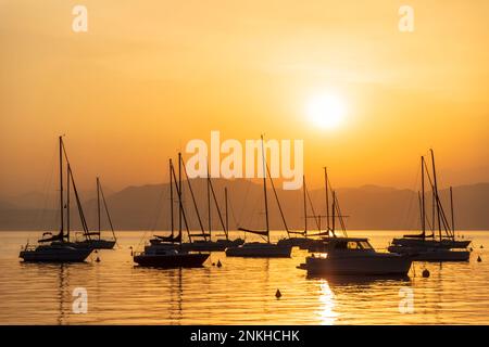 Italie, Vénétie, Bardolino, Silhouettes de voiliers flottant dans le lac de Garde au coucher du soleil Banque D'Images
