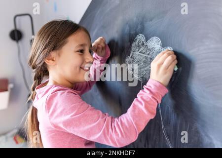 Bonne fille dessin avec craie à bord à la maison Banque D'Images