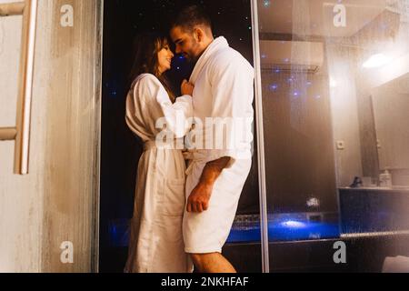 Couple romantique portant des peignoirs debout à la porte Banque D'Images