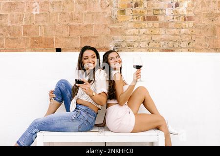 Heureux amis assis sur le banc avec des lunettes de vin Banque D'Images