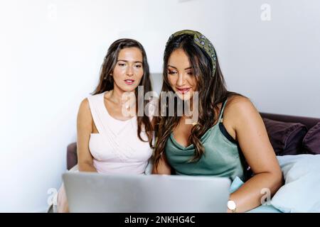 Des travailleurs indépendants travaillant ensemble sur un ordinateur portable à la maison Banque D'Images