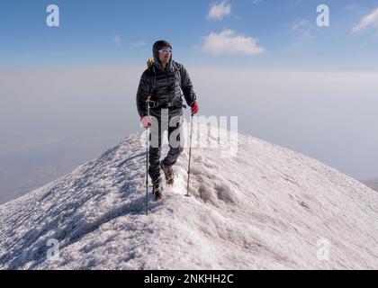 Homme randonnée sur une montagne enneigée le week-end Banque D'Images