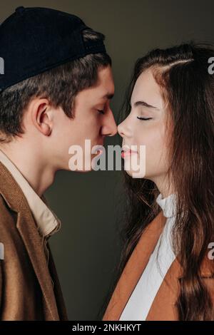 Couple adolescent aimant frottant le nez contre un fond gris Banque D'Images