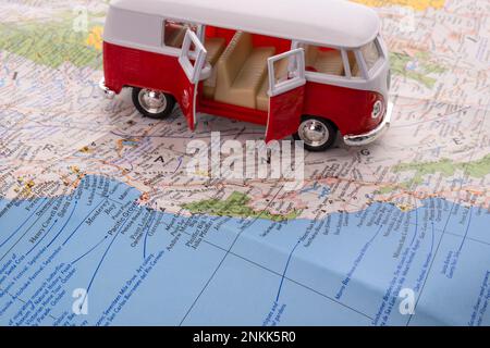 OGDEN, UTAH États-Unis - FÉVRIER 10 2023 gros plan d'une fourgonnette miniature VW rouge et blanc avec ses portes ouvertes sur une carte de la côte californienne montrant Monterey Banque D'Images