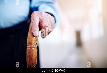 Marche régulière vers la bonne santé. Gros plan d'un homme âgé méconnu tenant la main sur un bâton de marche. Banque D'Images