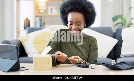 Bonne femme afro-américaine utilisant un appareil de contrôle du glucose à la maison. Femme noire souriante vérifiant son niveau de sucre avec un kit de résultats de test rapide Banque D'Images