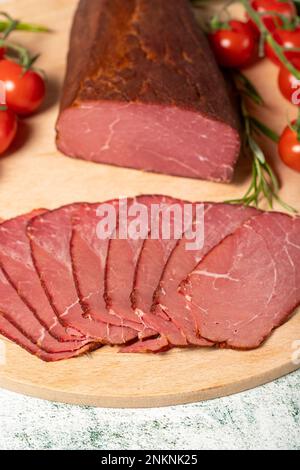 Viande sèche. Tranches de viande séchée et fumée sur un panneau de bois. Morceaux de bœuf saccadés Banque D'Images