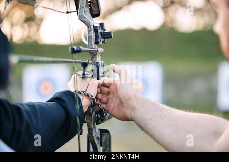Les mains, l'entraîneur de tir à l'arc et l'apprentissage de l'arc ou de la flèche pour la compétition archer, le défi de concentration d'athlète ou la pratique d'entraînement de fille. Enseignant, enseignant et homme Banque D'Images