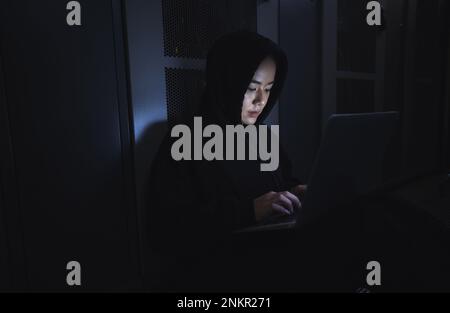 Hacker, salle de serveurs et personne sur ordinateur portable pour le codage de logiciels, le crime de centre de données et le cyberpunk dans l'obscurité. Piratage réseau, femme ou utilisateur dans la cybersécurité Banque D'Images