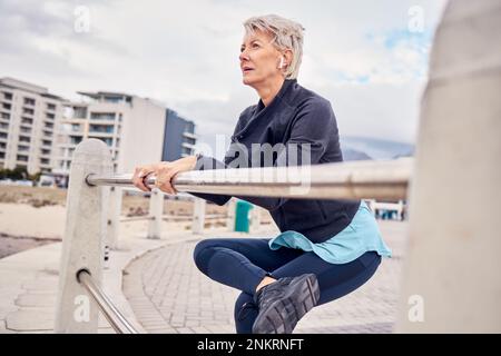 Fitness, musique et stretching avec une femme âgée se redy pour un entraînement cardio sur la promenade. Faites de l'exercice, réchauffez-vous et courez avec un adulte Banque D'Images