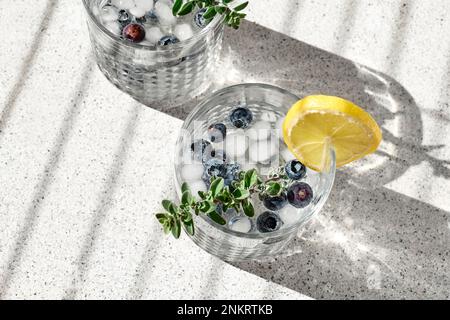 Boisson fraîche d'été mojito aux myrtilles ou limonade glacée aux myrtilles avec des tranches de citron, des myrtilles, de la glace et du thym. Banque D'Images