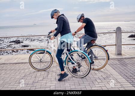 Vélo, vélo et remise en forme avec un couple senior sur la promenade, à cheval de transport écologique pour les voyages. Vélo, plage ou exercice avec un mature Banque D'Images