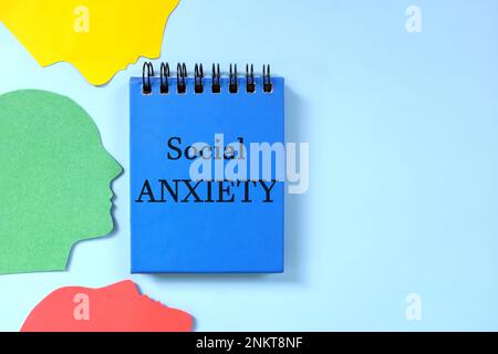 Concept de trouble d'anxiété sociale. Composition de pose plate de profil de tête humaine avec bloc-notes bleu. Banque D'Images