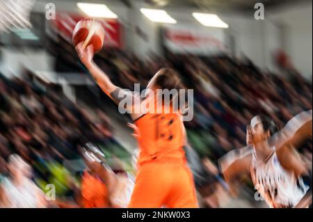 Une joueuse jette le ballon dans le panier pendant le match de basket-ball. Image avec défaut intentionnel (tatouage sur le bras également taché) Banque D'Images