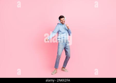 Grand cadre photo de la taille de jeune surjoyeuse humeur danse célébrer le week-end détente gars écouter de nouveaux écouteurs isolés sur fond de couleur rose Banque D'Images