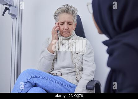 Aveugle, mal de tête et optométrie avec une patiente âgée dans un bureau d'opticien pour un test ou un examen oculaire. Médecin, douleur et médical avec une femme mature Banque D'Images