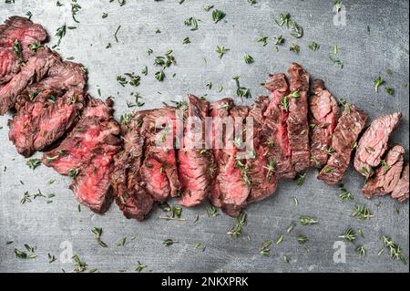 Steak de viande de bœuf haché grillé sur plateau en acier au thym. Arrière-plan noir. Vue de dessus. Banque D'Images