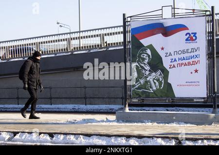 Moscou, Russie. 23rd févr. 2023. Un homme marche devant une affiche de propagande qui lit "pour la victoire! Pour nos employés! Pour la vérité» à Moscou. Vladimir Poutine a visité le jardin d'Alexandre pour déposer des fleurs à la tombe du Soldat inconnu près du mur du Kremlin. La Russie a célébré le défenseur de la Journée de la Patrie. Crédit : SOPA Images Limited/Alamy Live News Banque D'Images