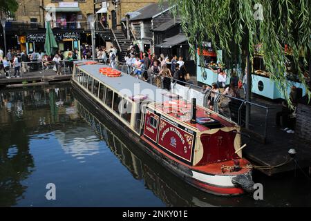 Un après-midi d'été chaud au populaire marché Camden Lock avec des gens qui font du shopping, achètent le déjeuner, se détendent et pendent avec des amis et des bateaux sur le canal Banque D'Images