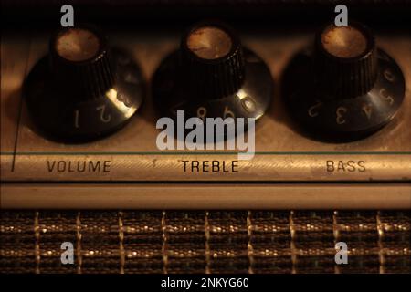 Boutons de réglage des aigus, du volume et des basses sur la tête de l'ampli guitare 1960s vintage. Température de couleur chaude, faible profondeur de champ, macro. Banque D'Images