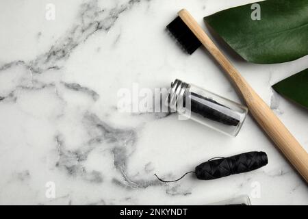 Composition de la couche plate avec des mousses dentaires biodégradables et une brosse à dents en bambou sur une table en marbre blanc. Espace pour le texte Banque D'Images