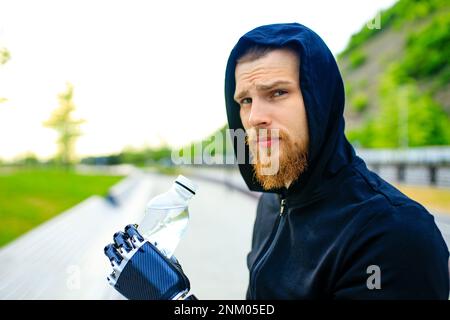 homme avec prothèse de bras dans des vêtements de sport prêts pour l'entraînement matinal à l'extérieur.Concept de sport pour handicapés Banque D'Images