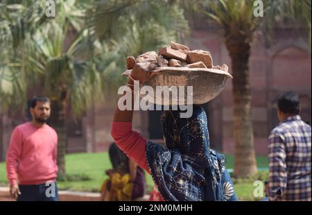 Une travailleuse portant un panier de briques sur la tête Banque D'Images