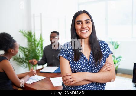 Portrait d'une femme d'affaires indienne souriante avec une équipe diversifiée dans la salle de réunion Banque D'Images
