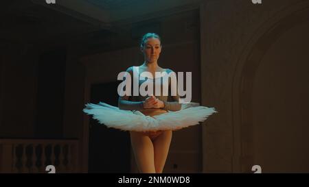 Réalisation cinématographique d'une ballerine gracieuse dans une robe de ballet debout dans le hall du théâtre après la répétition de chorégraphie, en regardant la caméra. Belle danseuse de ballet avant la représentation. Art classique du ballet Banque D'Images