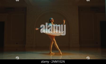 Prise de vue cinématique d'une magnifique danseuse de ballet classique en robe tutu blanche dansant dans la salle de théâtre et préparant le début de la représentation. Chorégraphie avant le début du spectacle. Ballet classique Banque D'Images