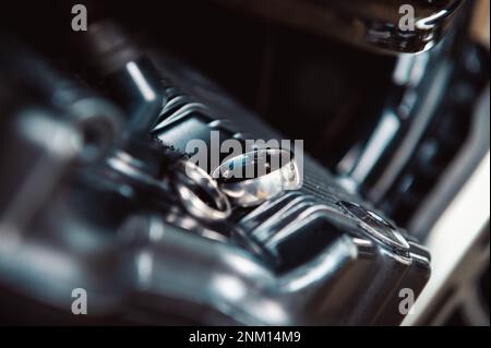 mains, anneaux de mariage et voeux de mariage blanc or anneaux de mariage posés sur un moteur de moto Banque D'Images