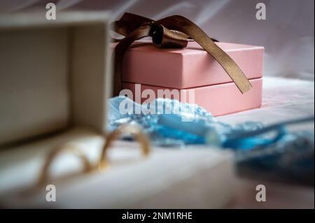 anneaux de mariage et détails une boîte blanche avec anneaux de mariage et une jarretière bleue couchée sur le lit sur fond de voile blanc Banque D'Images