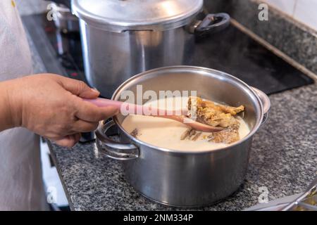 Remuer à la main la morue salée de la casserole en enlevant le sel avec le lait Banque D'Images