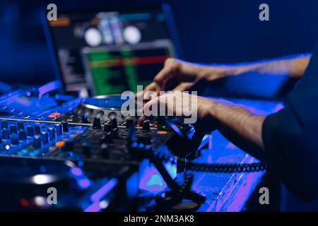 Des mains de DJ jouant de la musique sur une fête rave en boîte de nuit. DJ professionnel mélangeant des morceaux musicaux sur scène Banque D'Images