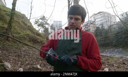 Coupe prudente : jeune homme Pruning des arbres avec précision et compétence Banque D'Images